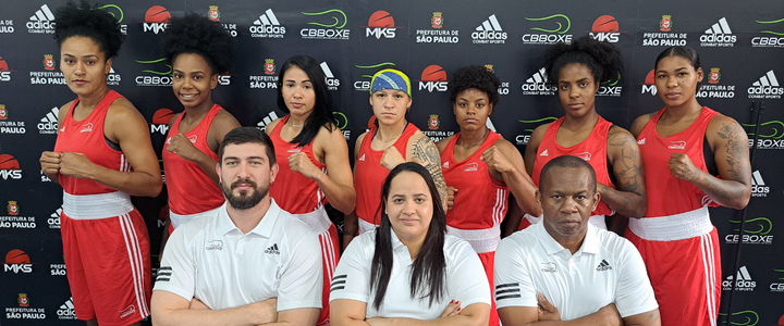 Atletas e treinadores do Brasil posam para foto. Atletas vestem um uniforme vermelho, enquanto os técnicos usam uma camisa polo branca